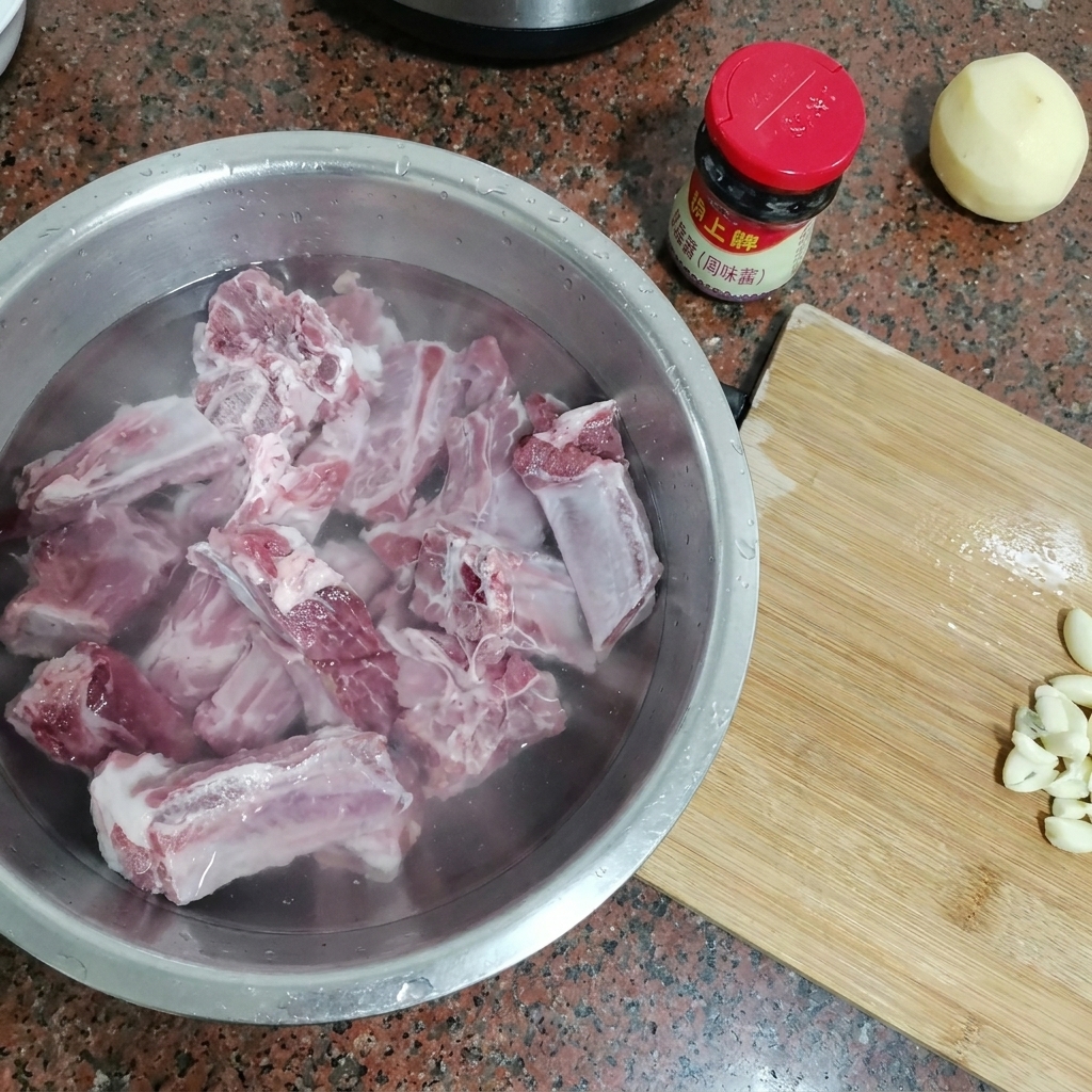 Rohe Schweinerippchen in einer großen Metallschüssel voller kaltem Wasser.