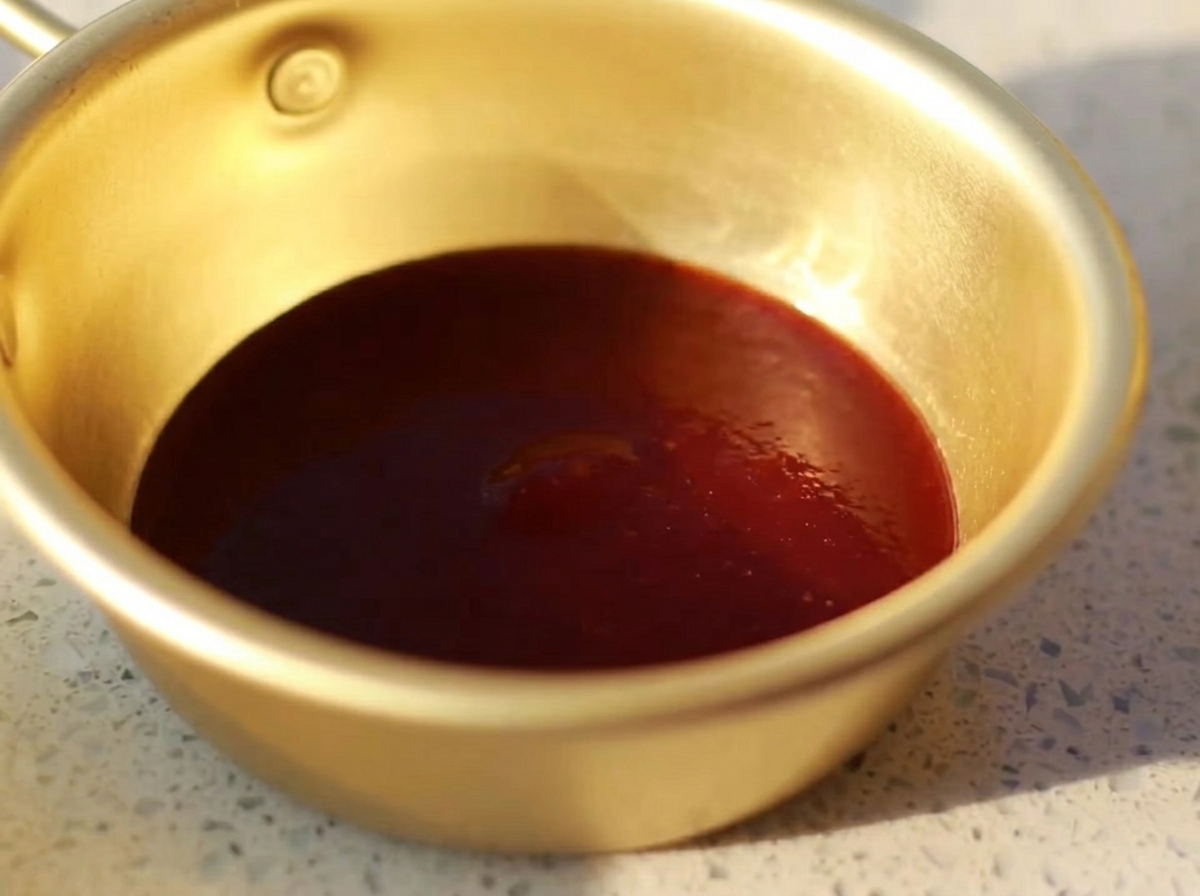 Eine kleine Metallschale mit einer glatten Mischung aus Barbecue-Sauce, Austernsauce, Senf, Honig und heller Sojasauce.