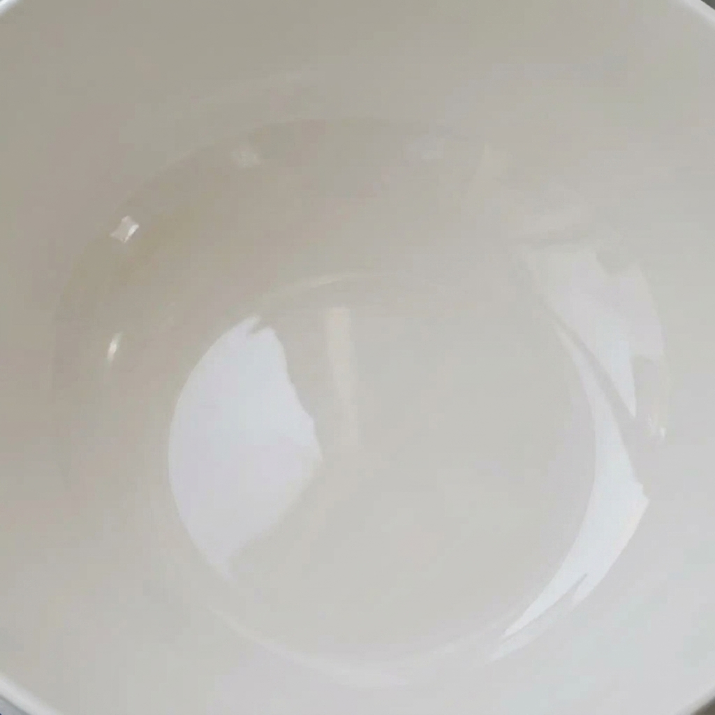 Frische Muscheln in einer weißen Schüssel mit klarem Wasser zum Entsandungsvorgang.