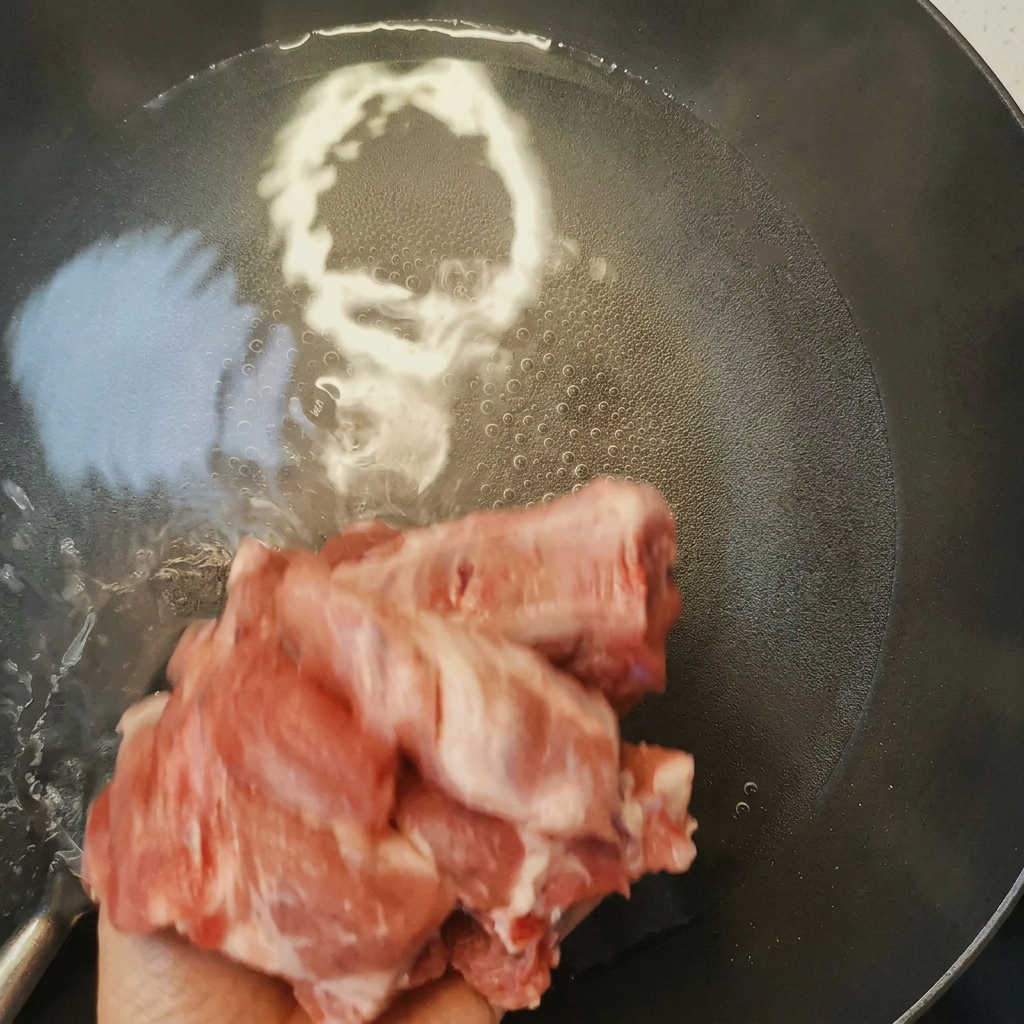 Schweinerippchen werden in kochendem Wasser mit Kochwein blanchiert, wobei Schaum an die Oberfläche steigt.