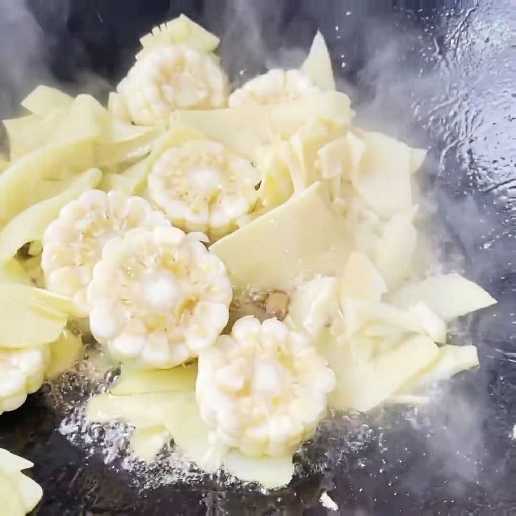 Klares Wasser wird in einen Wok zu den angebratenen Zutaten gegossen, um die Suppe zu starten.
