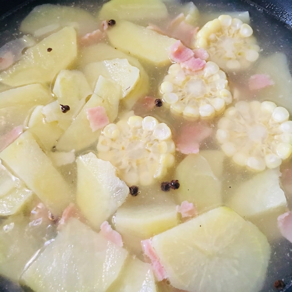 Ausgelöstes Muschelfleisch wird in den Topf mit der köchelnden Suppe gegeben.