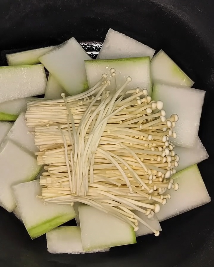 Enoki-Pilze werden auf das Bett aus Wintermelonenscheiben im Topf gelegt.