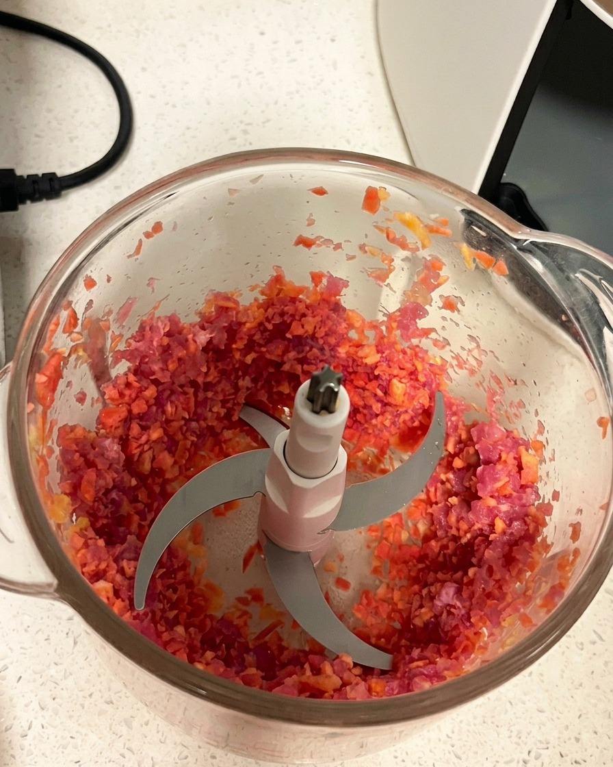 Gehackte Schweinefleisch-Karotten-Mischung mit gleichmäßiger Konsistenz im Mixerbehälter.