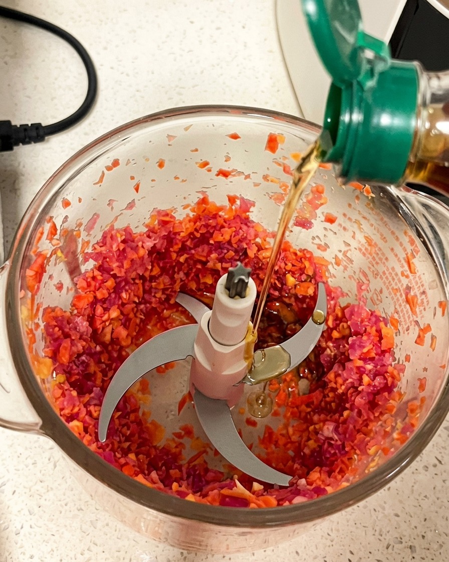 Das gehackte Fleisch im Mixerbehälter, während verschiedene Saucen hinzugefügt werden.