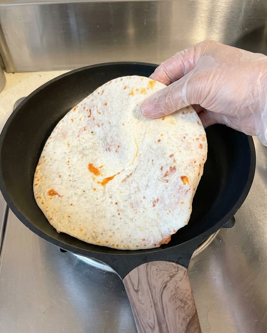 Ein Pfannkuchen wird in einer heißen Pfanne angebraten.