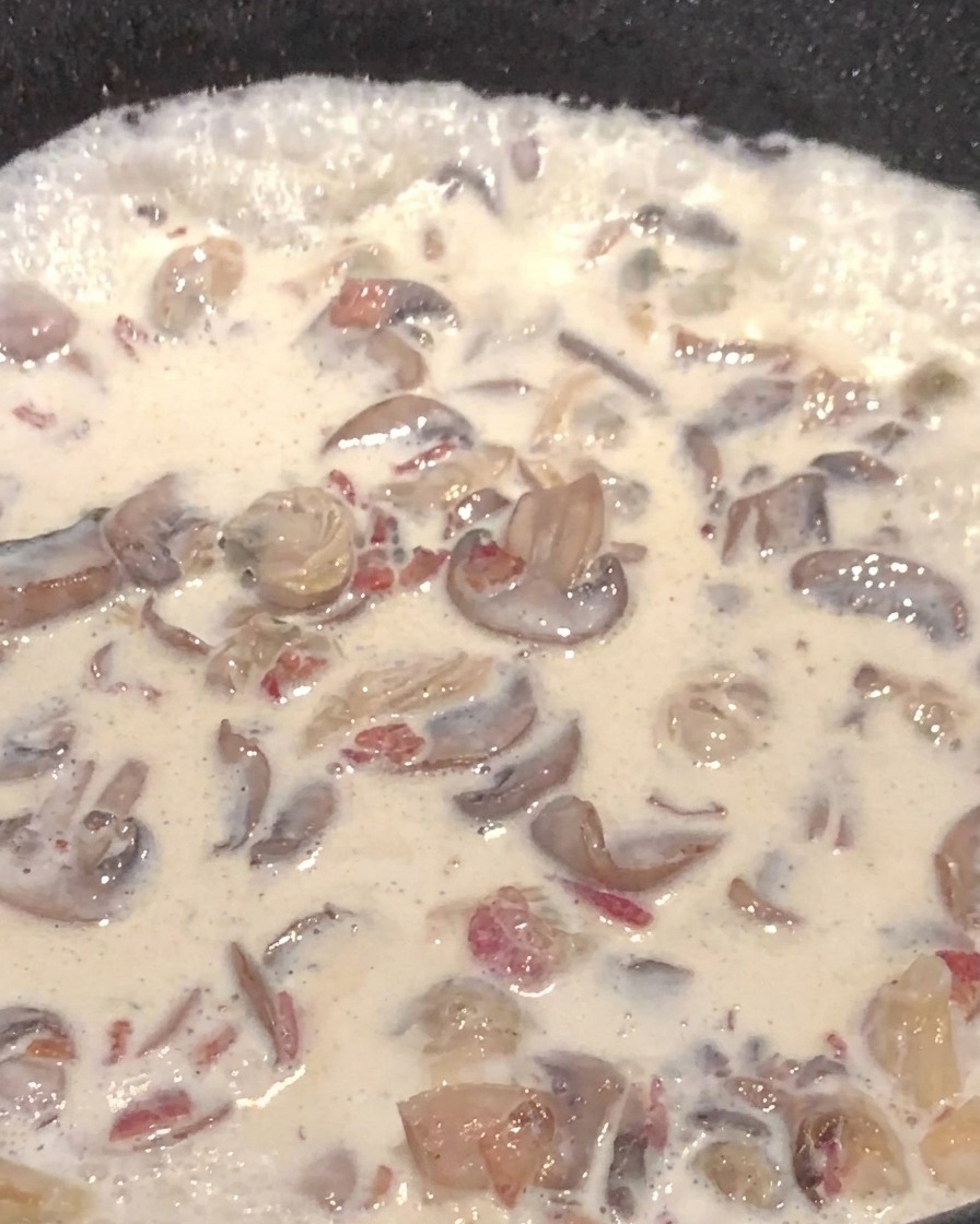 Cremige Pilzsuppe mit Kartoffelwürfeln in einer Pfanne.