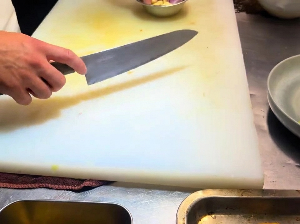 Dünn geschnittene Knoblauchzehen auf einem weißen Schneidebrett.
