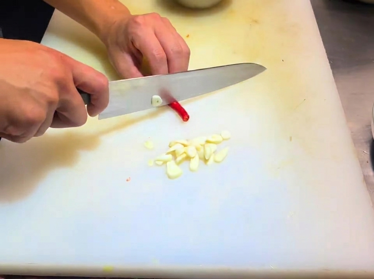 Geschnittene Schalotten und Chilischoten auf einem Schneidebrett.