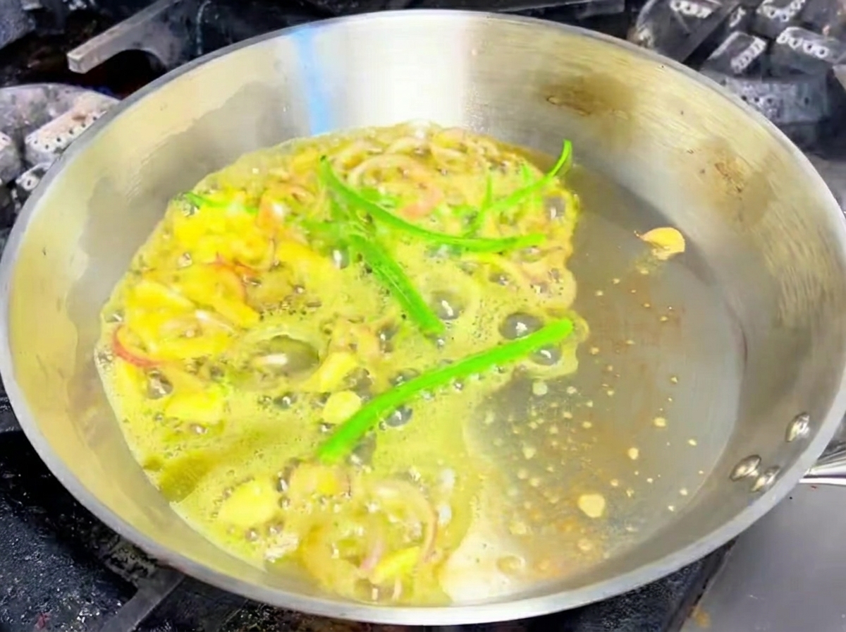 Geschnittener Knoblauch, Schalotten und grüne Chilischoten in der Pfanne.