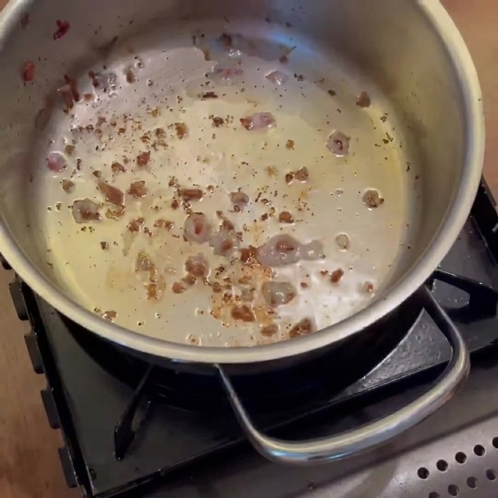 Zwiebeln, Karotten und Kartoffeln dünsten im Topf im Speckfett, bis sie glasig sind.