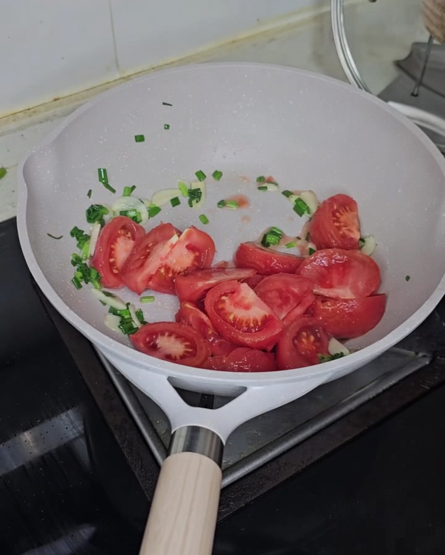 Gewürfelte frische Tomaten werden zu den gebratenen Aromaten in die Pfanne gegeben.