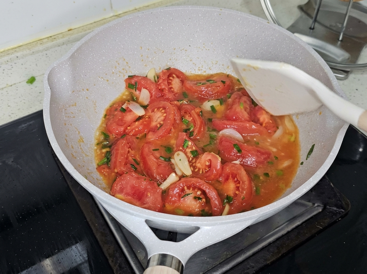 Kochendes Wasser wird in die Pfanne über die angebratenen Tomaten gegossen.