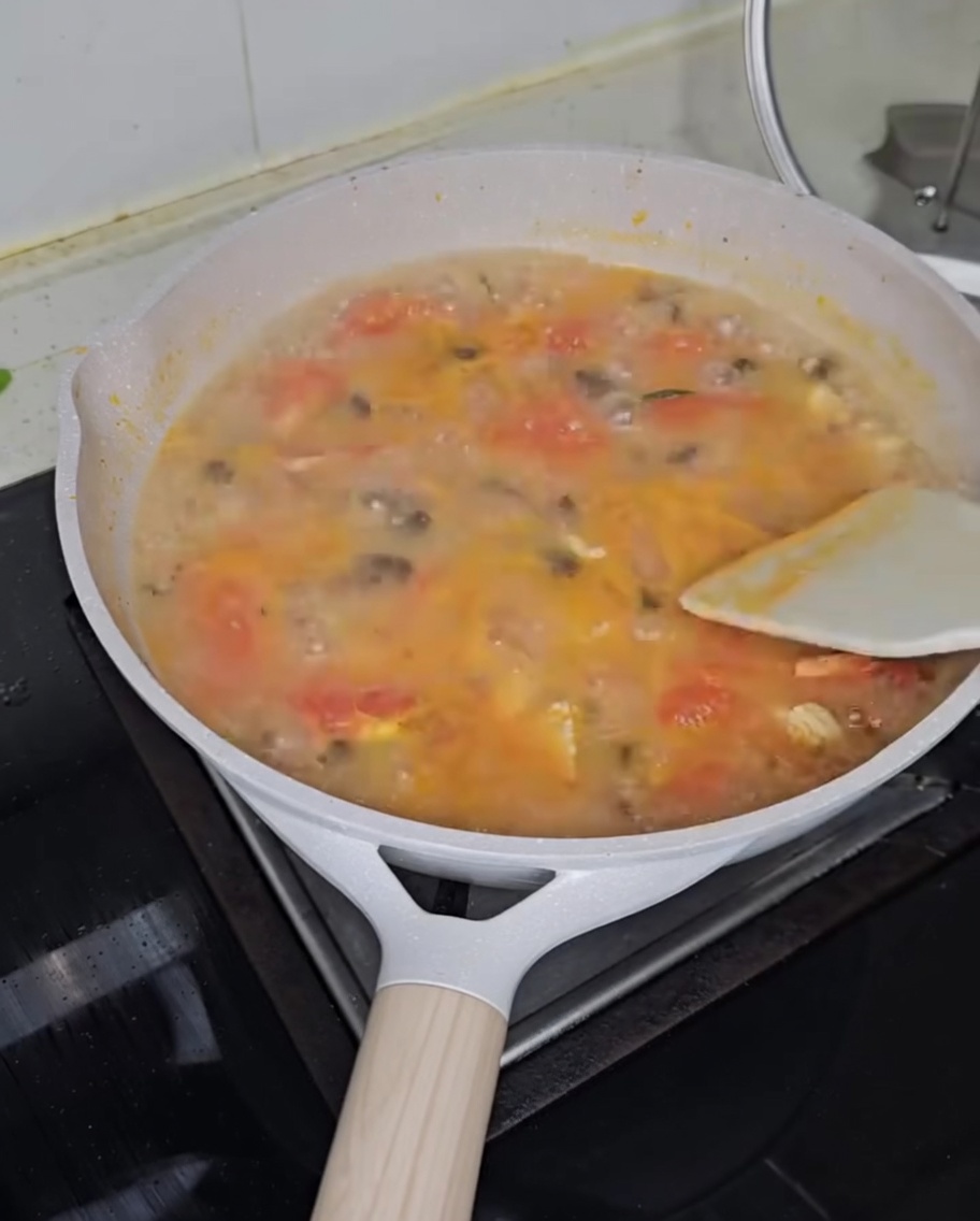 Frisch gehackte Frühlingszwiebeln werden über die dampfende Tomaten-Hähnchen-Suppe gestreut.