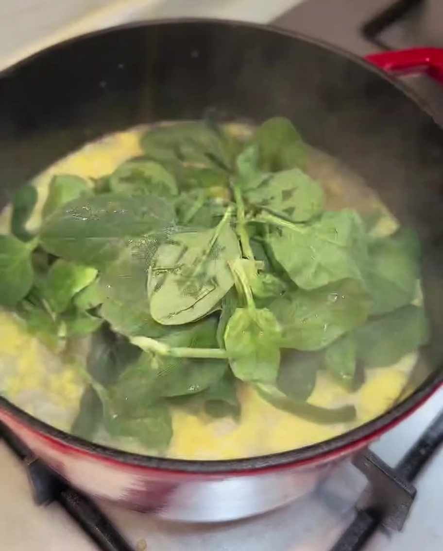 Frische Spinatblätter werden in den Topf mit fertiger Hühnersuppe gerührt.