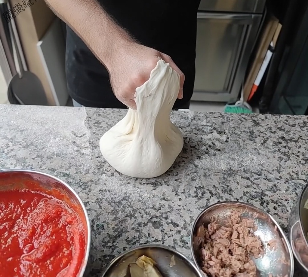 Der Chef dehnt den Pizzateig, indem er ihn über seine Knöchel dreht.