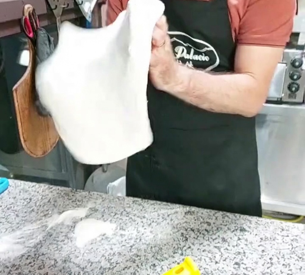 Ein Pizzateigboden wird in der Luft geformt.