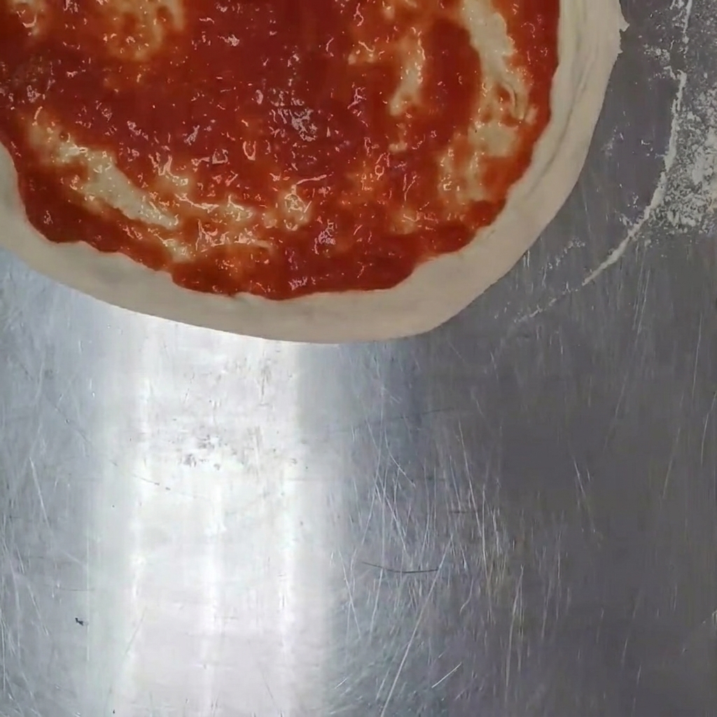 Handgezupfter Mozzarella wird auf der Tomatensauce verteilt.