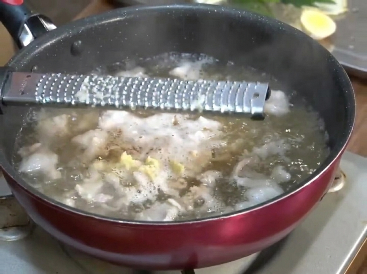 Frisch geriebener Knoblauch und Ingwer werden in die köchelnde Brühe gegeben.