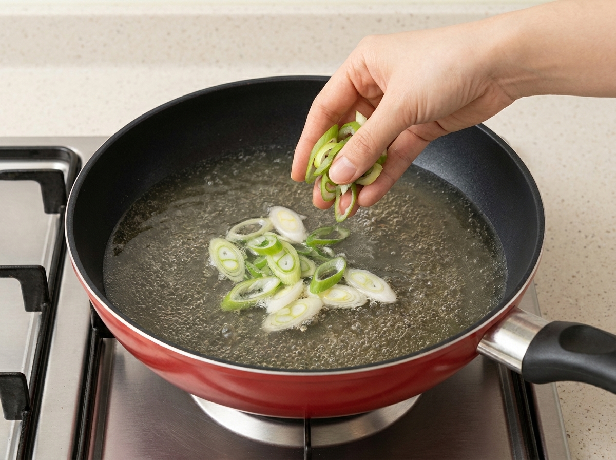 Frisch geschnittene Frühlingszwiebeln und Sojasprossen werden zur Ramen-Suppe gegeben.