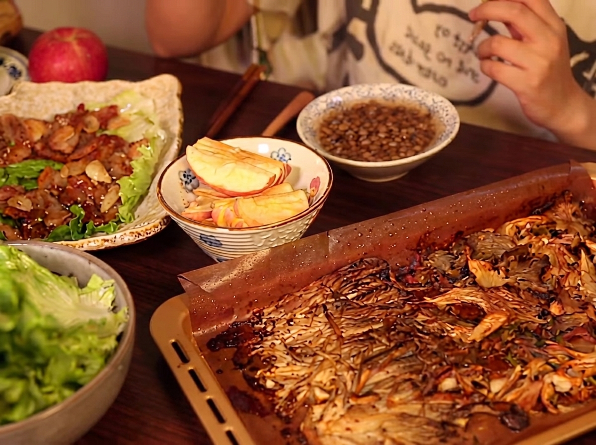 Eine Saucenmischung wird über den bräunenden Schweinebauch in der Pfanne gegossen.