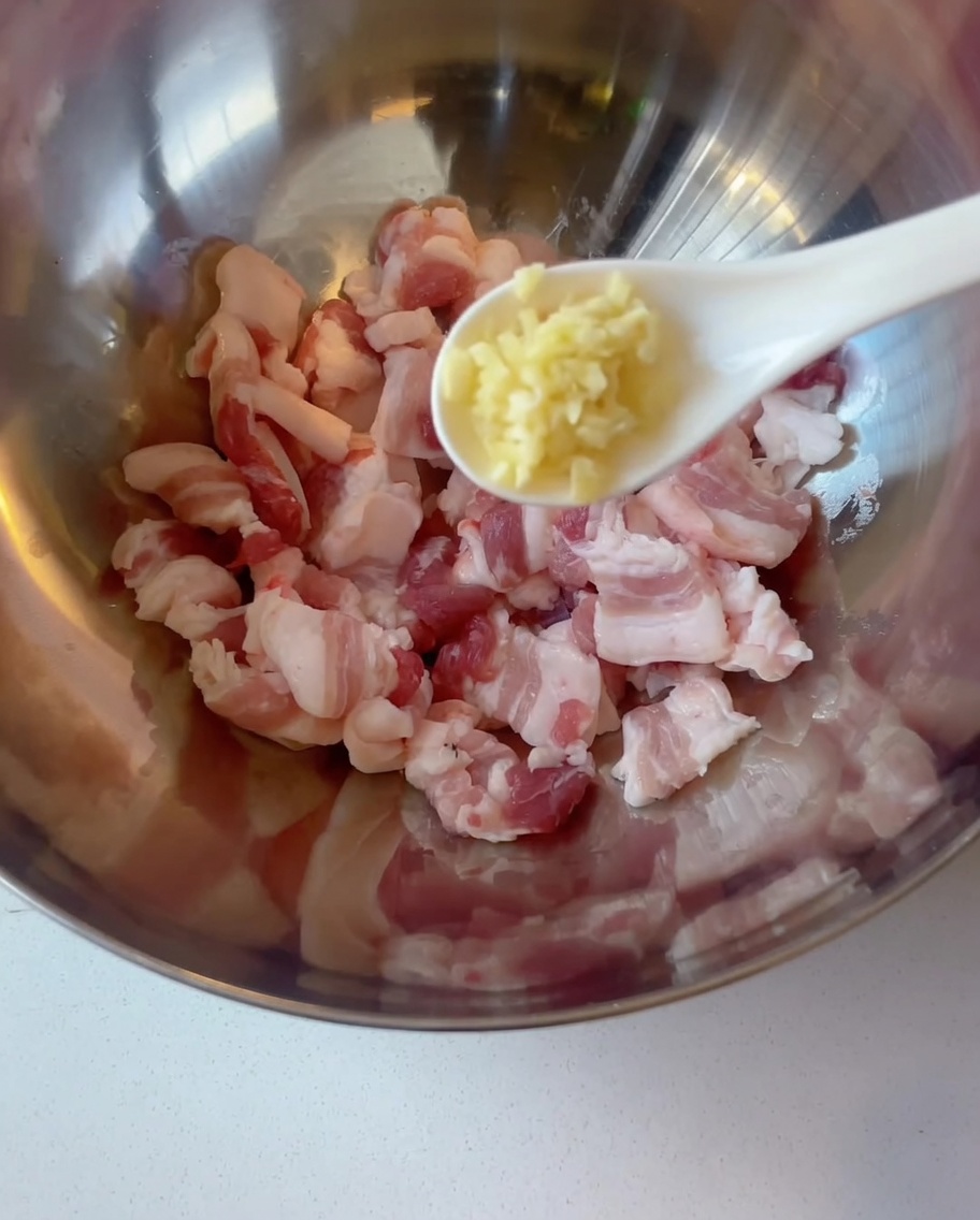 Schweinebauchscheiben in einer Schüssel mit Knoblauch.