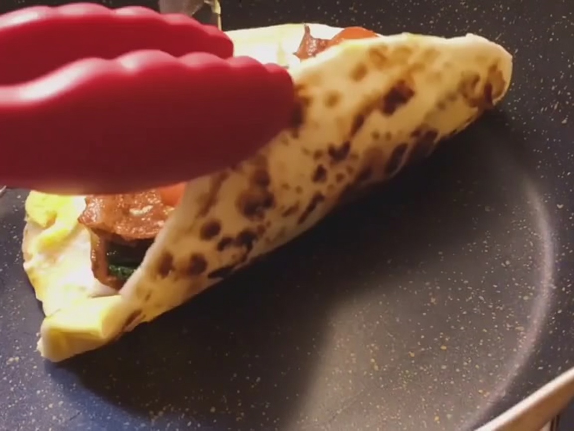 Ein frisch zubereiteter Frühlingszwiebel-Fladenbrot-Wrap wird auf einer glatten Oberfläche eng zu einer Rolle geformt.