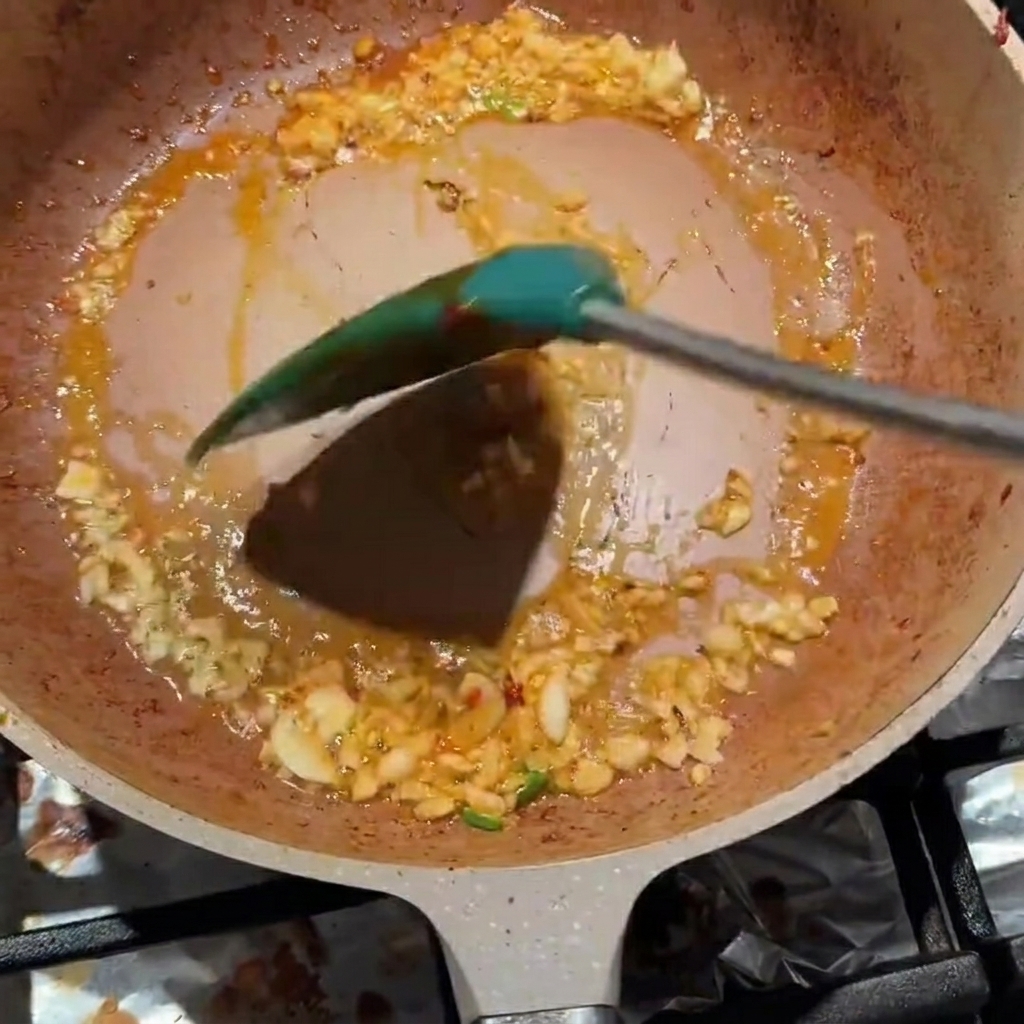 Gehackter Knoblauch und Pixian-Bohnenpaste werden in der Pfanne verrührt.