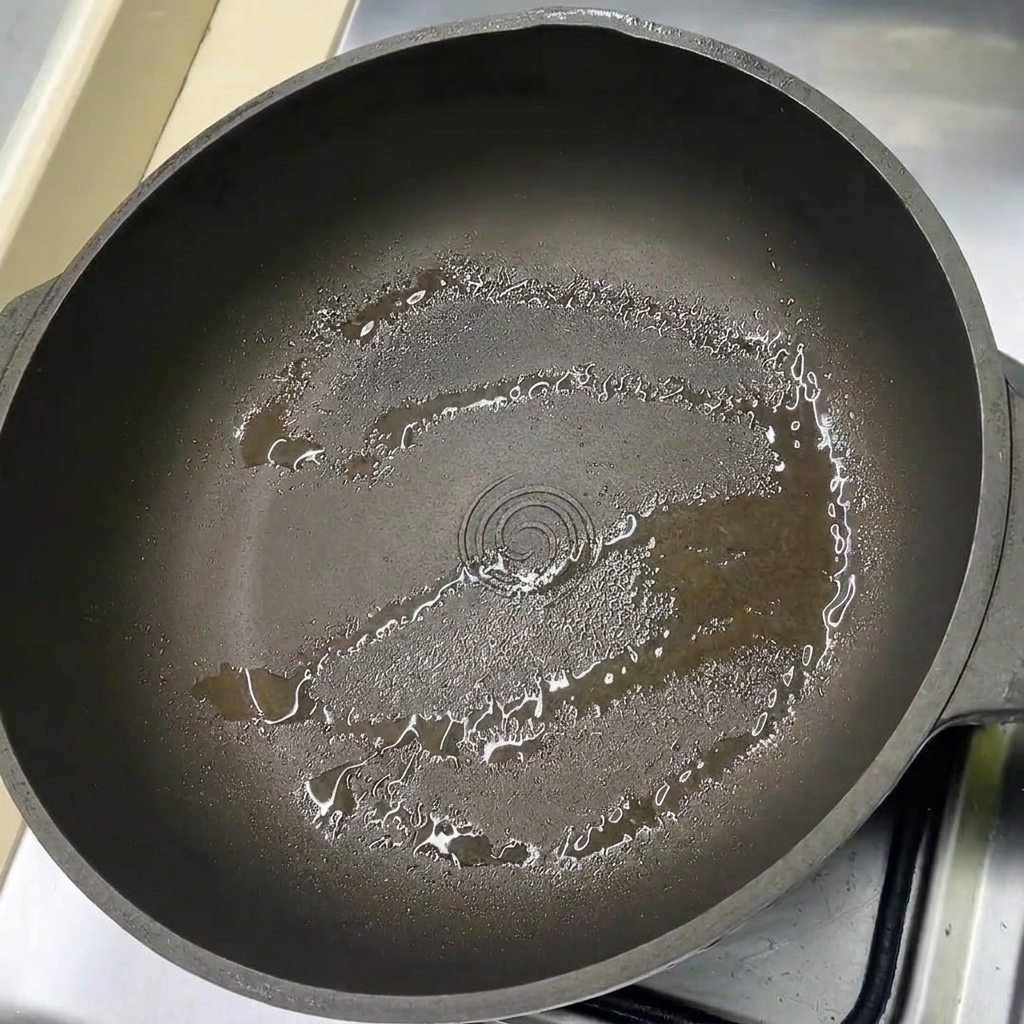 Schweinebauchscheiben liegen in einer leicht geölten Pfanne.