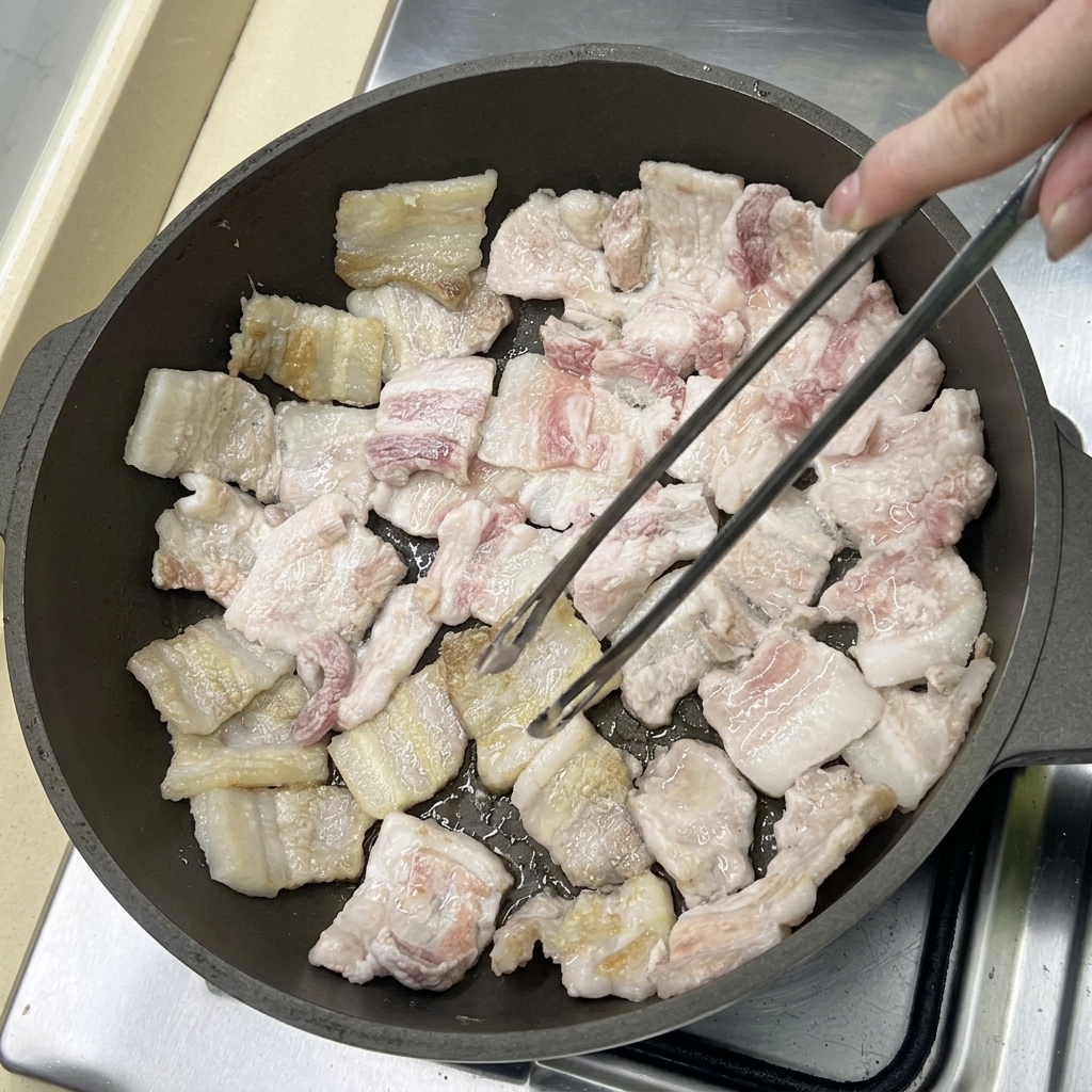 Schweinebauchscheiben braten in der Pfanne und werden goldbraun.