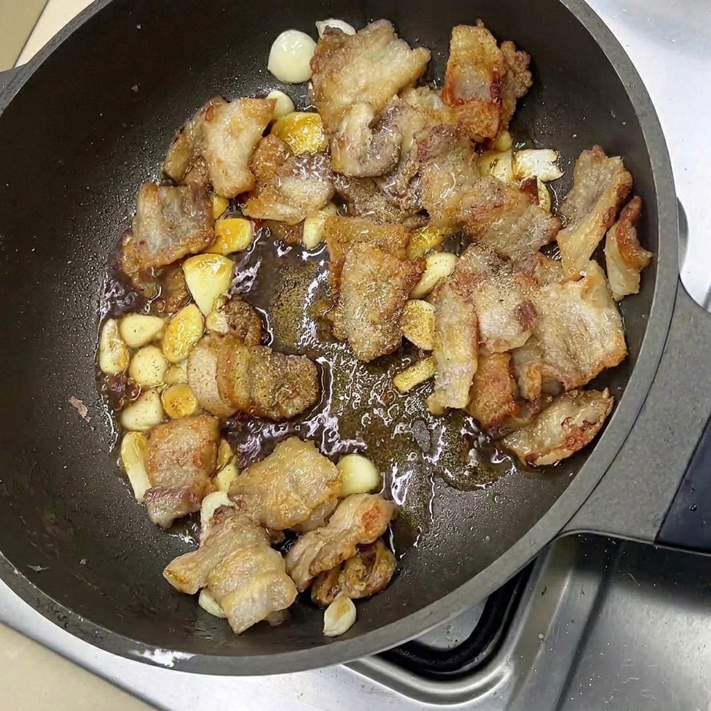 Glasiertes Schweinefleisch mit Knoblauch in der Pfanne.