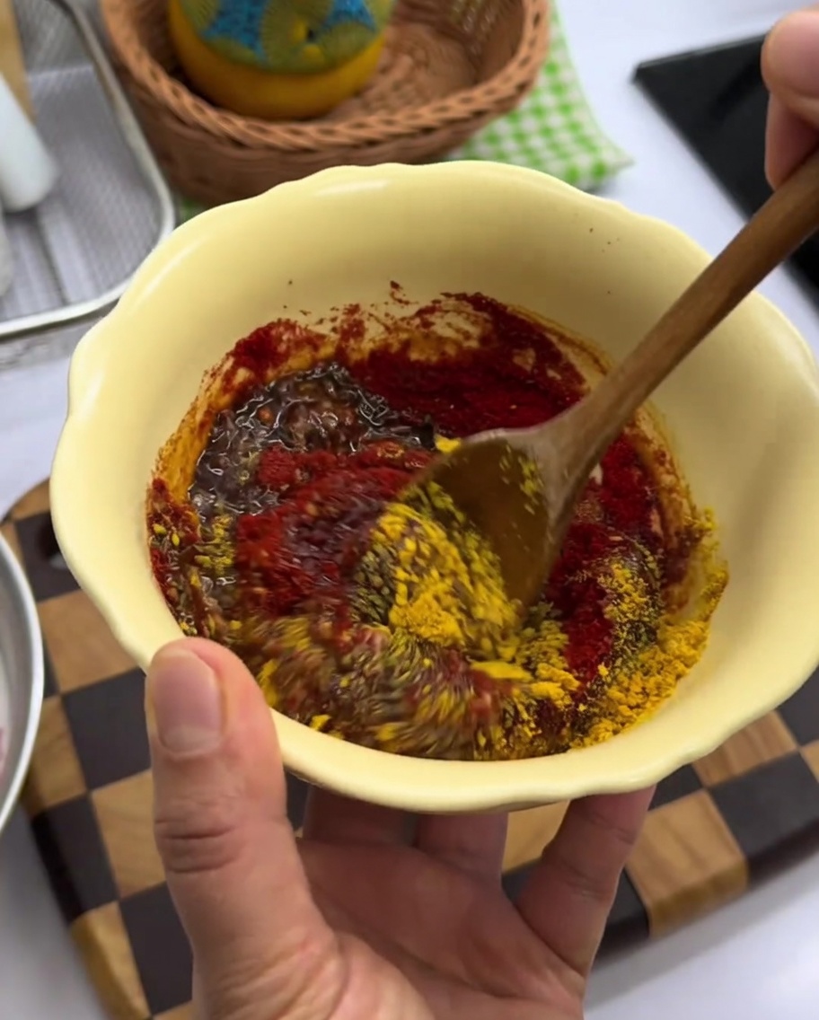 Dicke rote Gewürzpaste in einer gelben Schüssel.