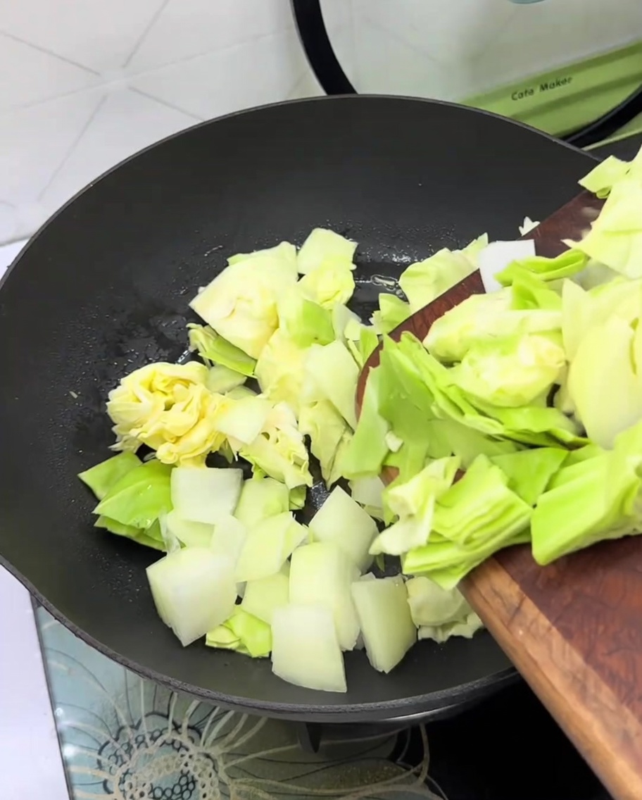 Frischer Kohl und Zwiebelscheiben in einer leeren Pfanne.