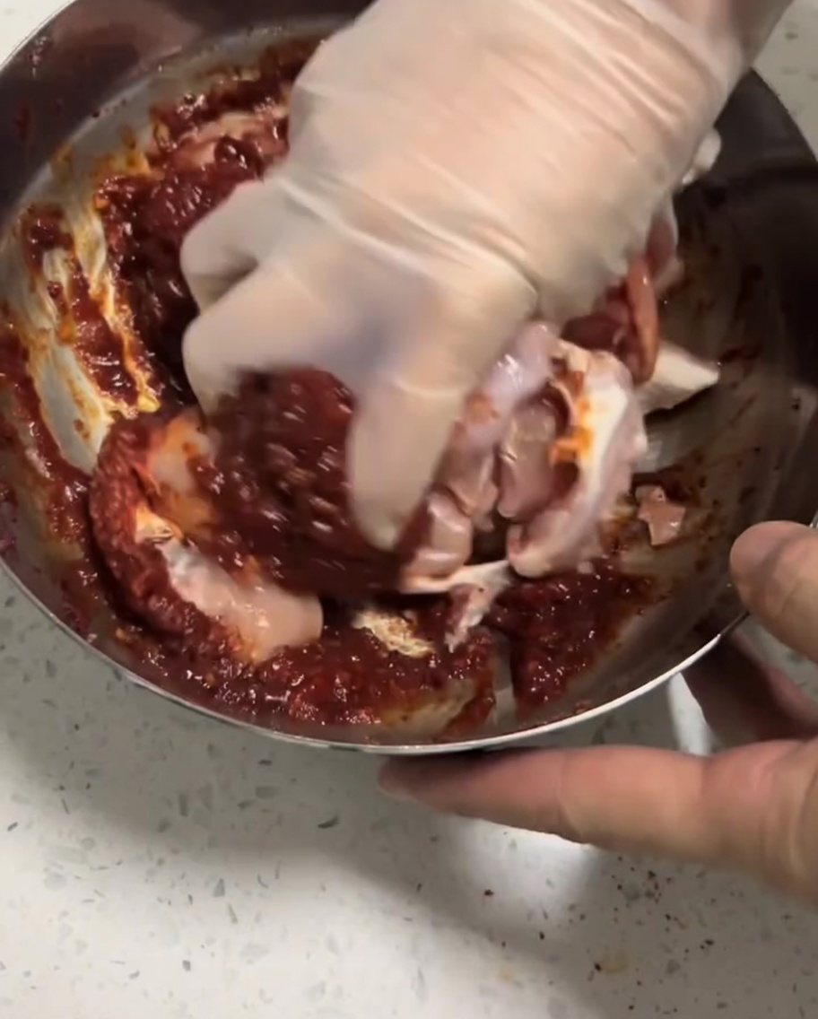Die Hähnchenstücke werden in der Schüssel mit der Marinade vermengt.