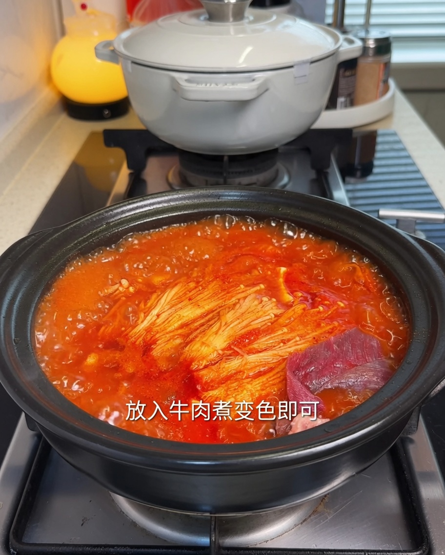 Zarte marinierte Rindfleischscheiben werden in die heiße Kimchi-Tofu-Suppe gegeben.