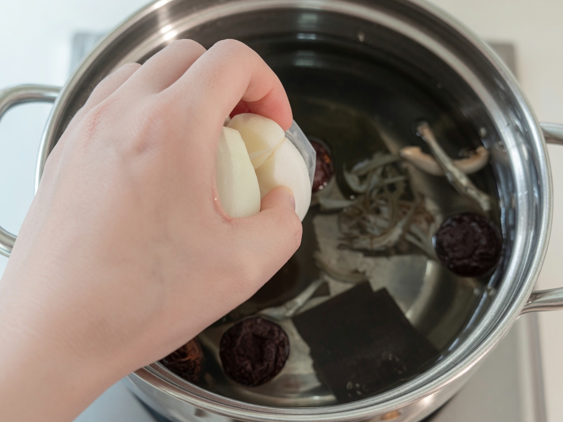 Kochendes Wasser in einem Topf mit Kombu, Sardellen, Shiitake-Pilzen, Zwiebel und Rettich.
