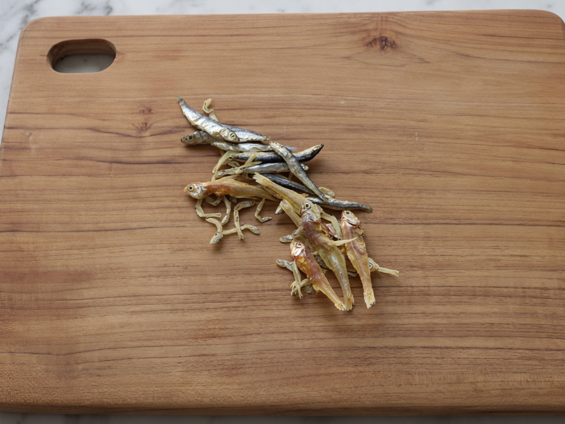 Getrocknete Sardellen auf einem Holzbrett, bei denen Köpfe und Eingeweide entfernt wurden.