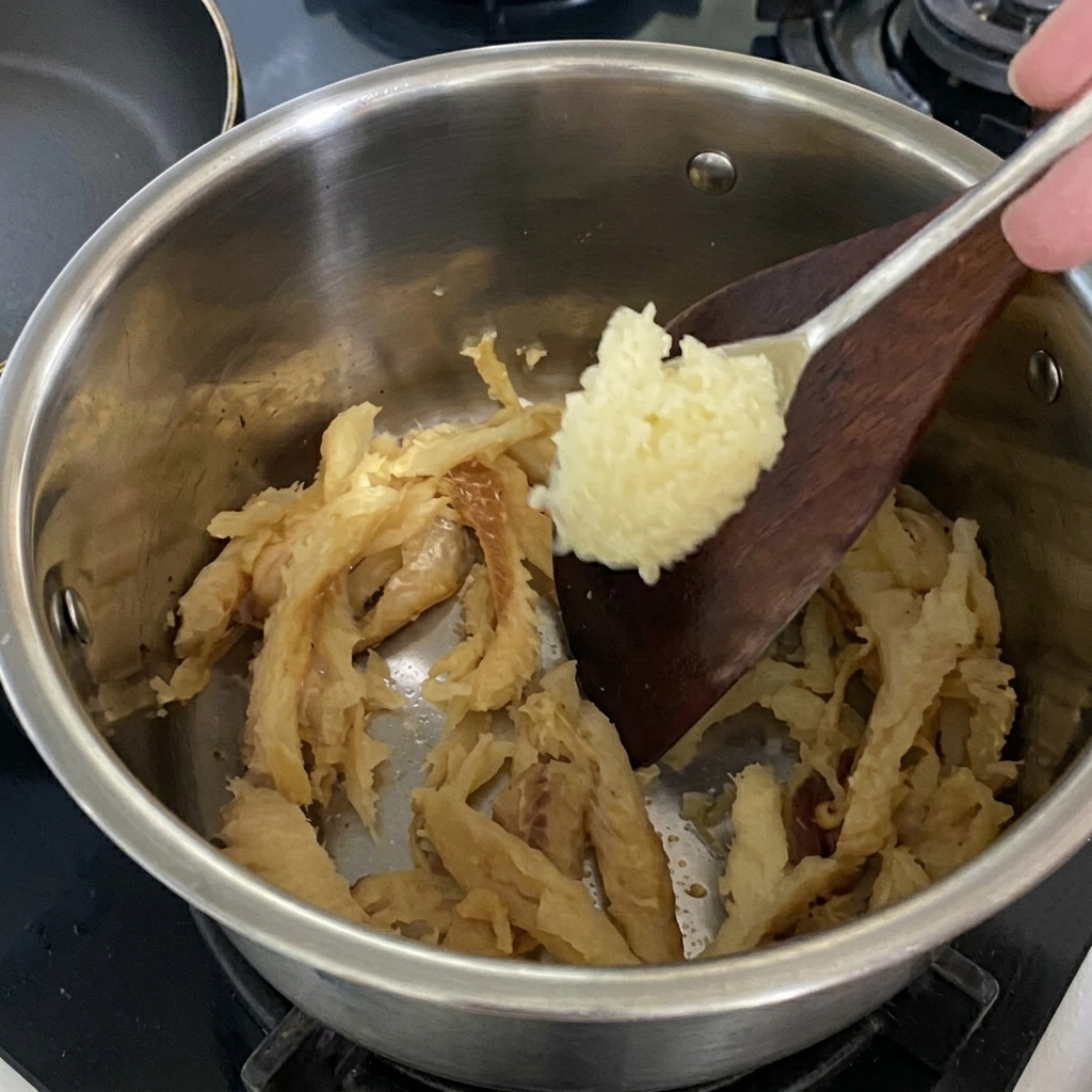 Gehackter Knoblauch wird zu dem in der Pfanne angebratenen Pollack gegeben.