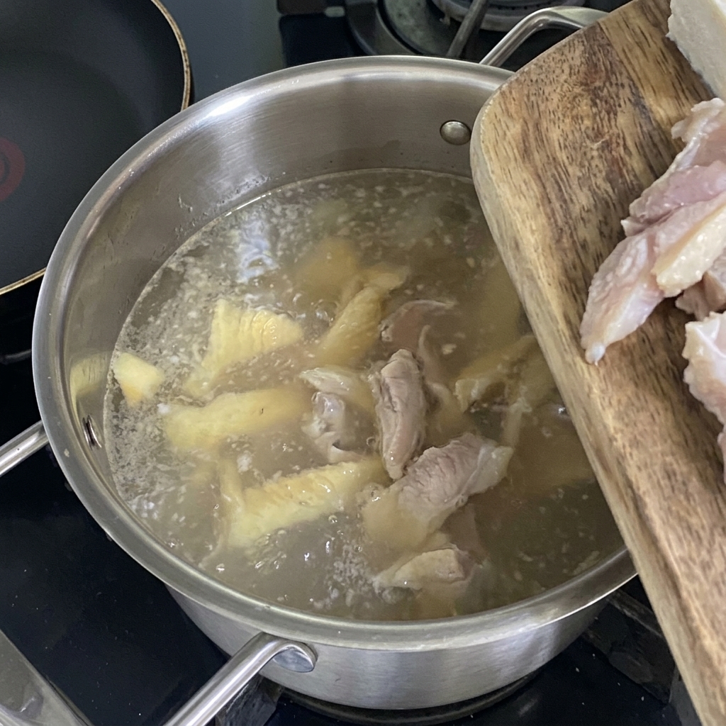 Frische Tofuwürfel werden in die köchelnde, helle Pollack-Brühe gegeben.
