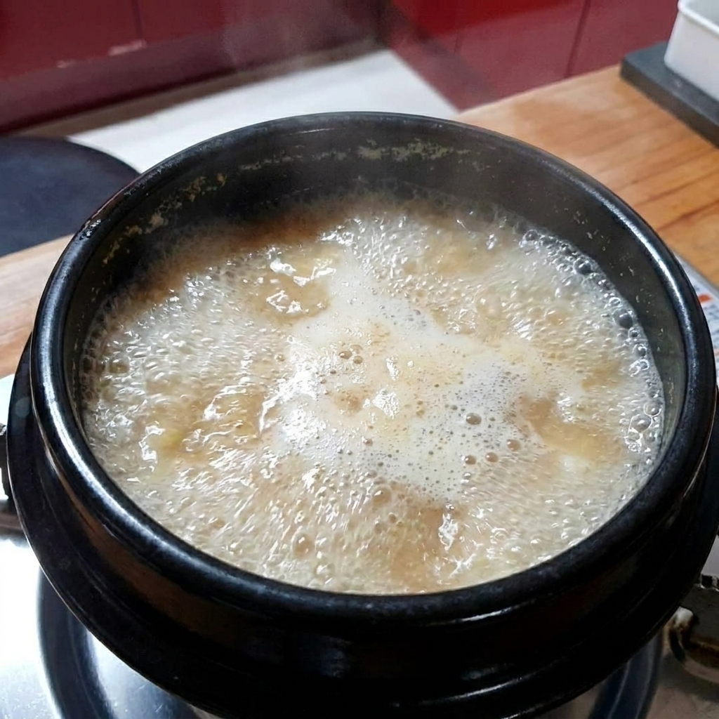Gehackter Knoblauch wird in den kochenden Sojabohneneintopf gegeben.