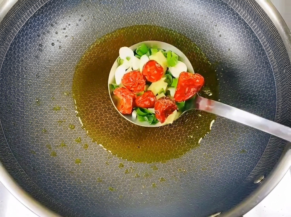 Gehackte Frühlingszwiebeln, Knoblauchscheiben und getrocknete Chilis braten im heißen Öl.