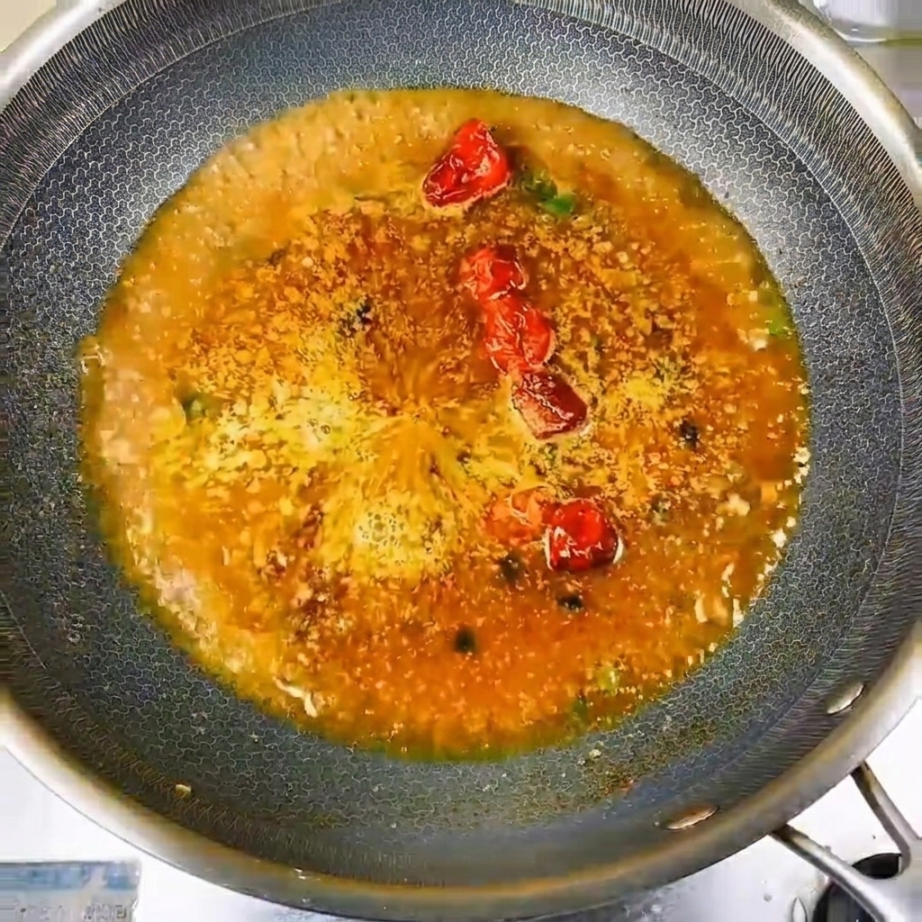Kleine, frische Flussfische, sorgfältig im Kreis in der würzigen, köchelnden Flüssigkeit angeordnet.