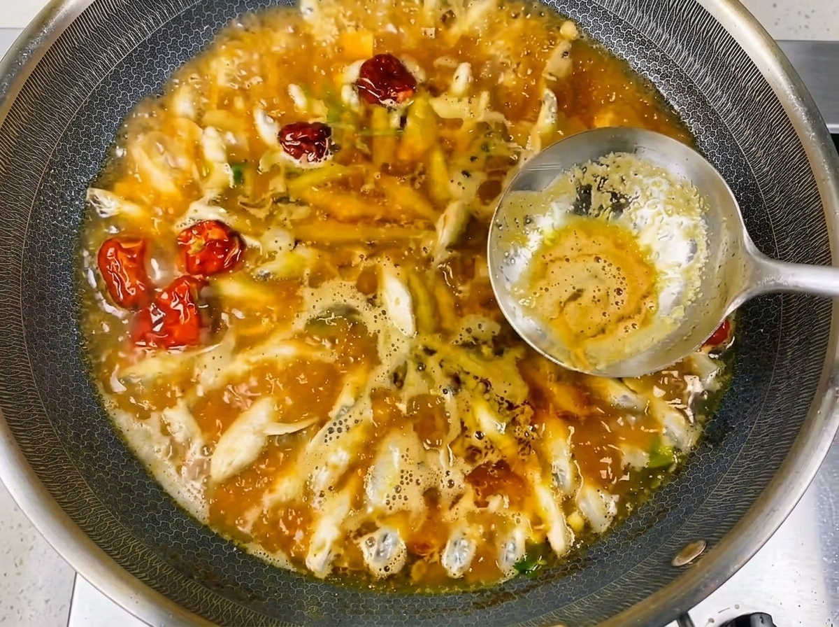 Nahaufnahme des in einer reichhaltigen, herzhaften Brühe köchelnden kleinen Flussfisches.