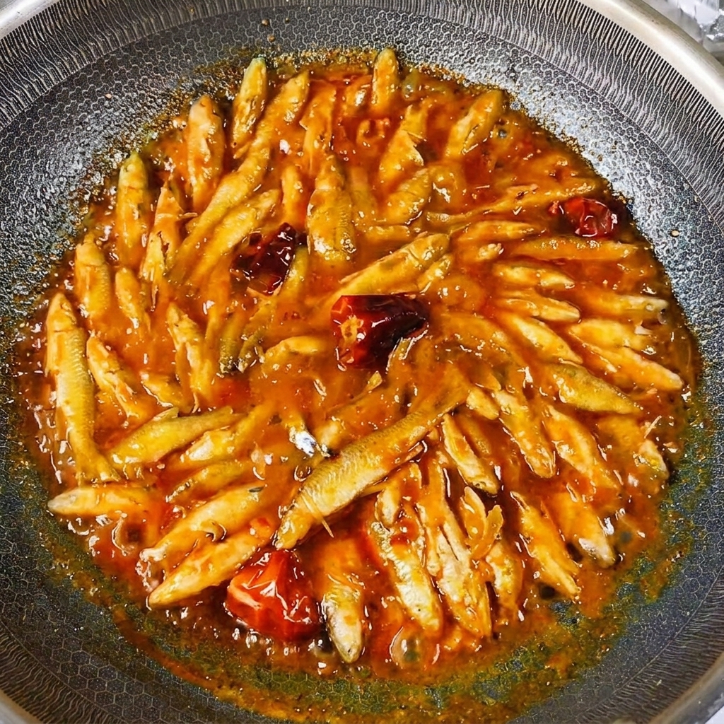 Der fertig gegarte Flussfisch, glänzend überzogen mit einer dicken, herzhaften Soße im Wok.