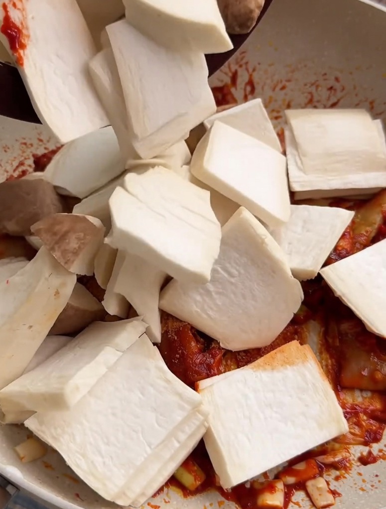 Geschnittene Kräuterseitlinge werden in eine Pfanne geworfen und mit einer roten, würzigen Würzpaste vermischt.