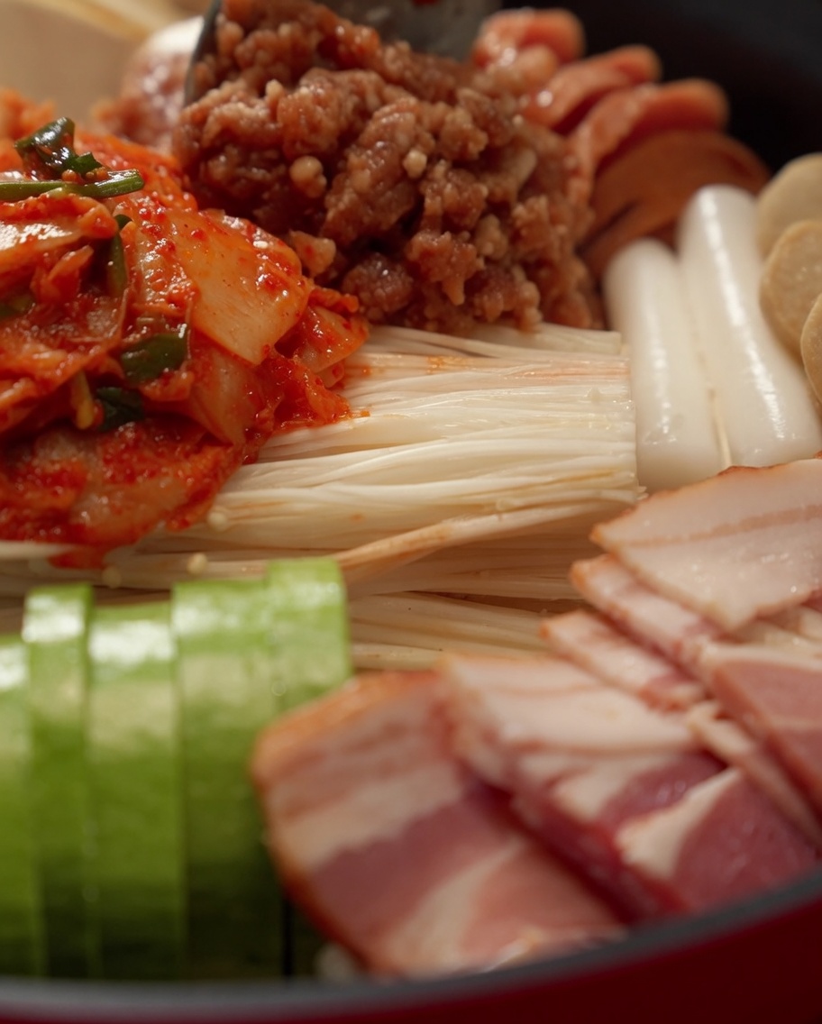 Die zubereitete rote Saucenmischung und Wasser werden über die zusammengestellten Hot-Pot-Zutaten gegossen.