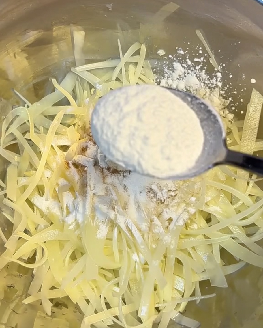 Schüssel mit geriebenen Kartoffeln, die mit einer Mischung aus Mehl und Maisstärke bestäubt werden.