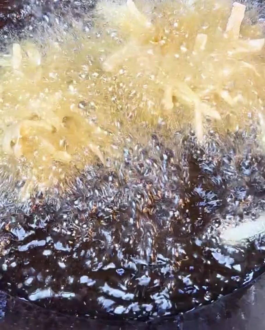 Knusprige Kartoffelraspeln, die in sprudelnd heißem Öl goldbraun frittiert werden.