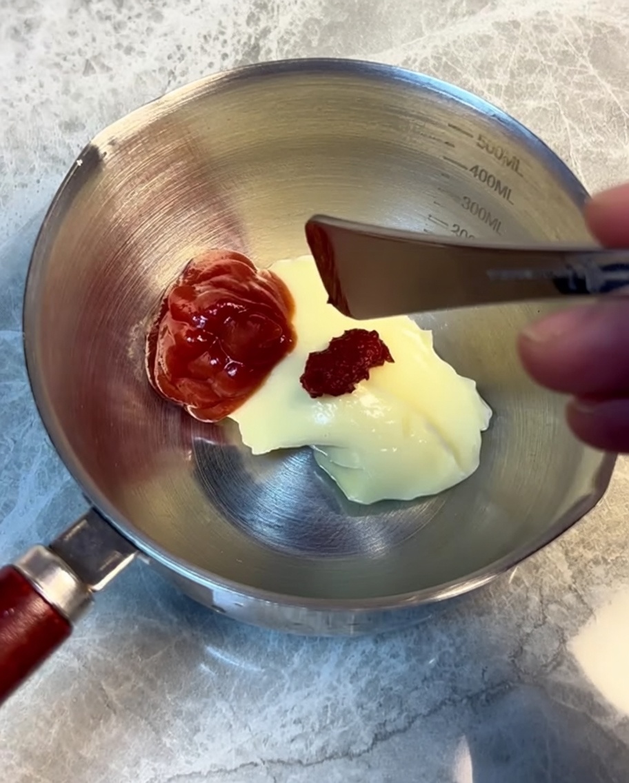 Zutaten für die Burgersauce werden in einem Edelstahlbecher verrührt.