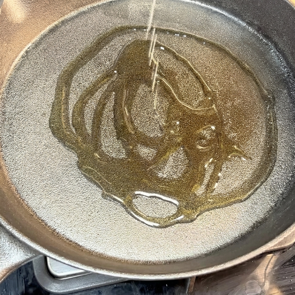 Gewürztes Rindfleisch-Patty, das in einer heißen Gusseisenpfanne mit Öl zischt.